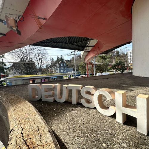 Kreisrundes Bild, das das Wort "Deutsch" in dreidimensionalen Lettern in weiss zeigt.