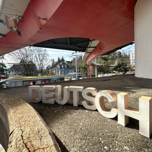 Kreisrundes Bild, das das Wort "Deutsch" in dreidimensionalen Lettern in weiss zeigt.